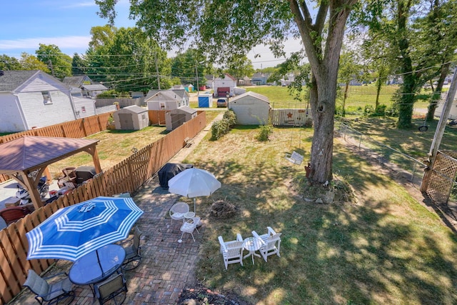 view of yard featuring an outbuilding, a gazebo, a fenced backyard, a storage unit, and a patio