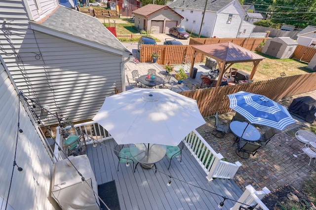 wooden terrace featuring a storage shed, an outbuilding, a fenced backyard, a patio, and outdoor dining space