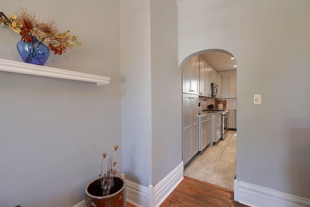 hall featuring baseboards and arched walkways