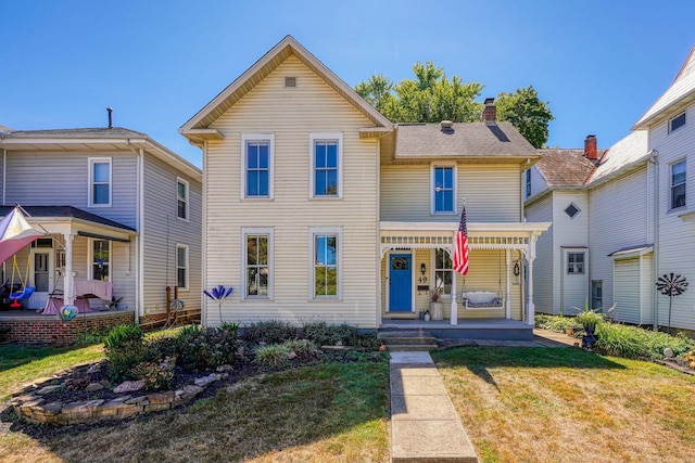 view of front of house featuring covered porch, a chimney, and a front yard