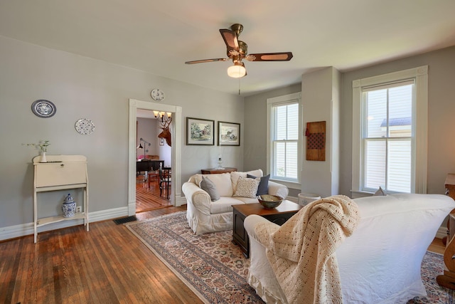 living area featuring baseboards, a ceiling fan, and dark wood-style flooring