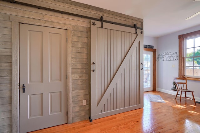 interior space with baseboards, a barn door, and light wood-style flooring