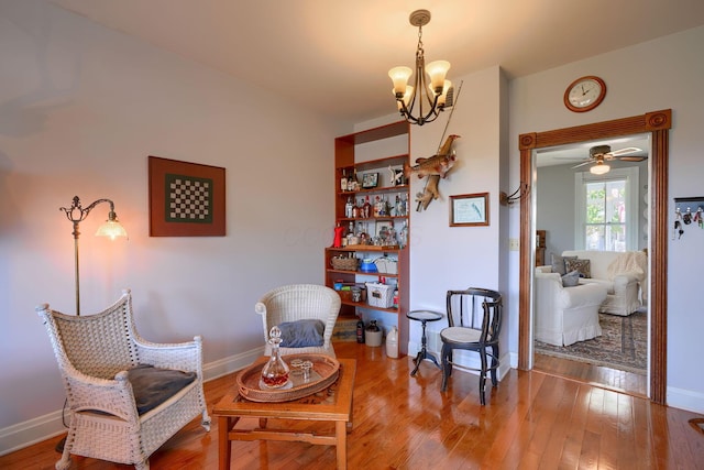 sitting room featuring an inviting chandelier, baseboards, and hardwood / wood-style flooring