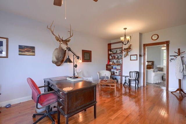 office space featuring light wood-type flooring, baseboards, and ceiling fan with notable chandelier