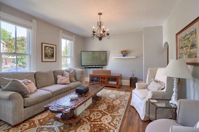living room with arched walkways, baseboards, a notable chandelier, and wood finished floors