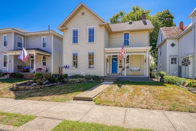 view of front of property featuring a porch, a chimney, and a front yard