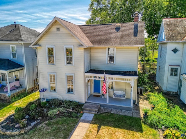view of front of house featuring a front yard, roof with shingles, a chimney, a patio area, and central air condition unit