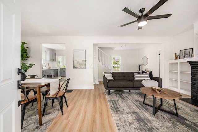 86 Hiawatha Ave, Westerville, OH 43081 - living area featuring light wood-style floors, a brick fireplace, a ceiling fan, baseboards, and stairway