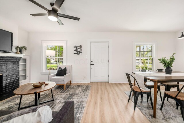 86 Hiawatha Ave, Westerville, OH 43081 - living room featuring a brick fireplace, a ceiling fan, a wealth of natural light, and light wood finished floors