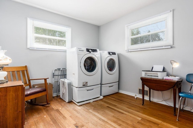 laundry room with laundry area, visible vents, washing machine and dryer, baseboards, and light wood finished floors