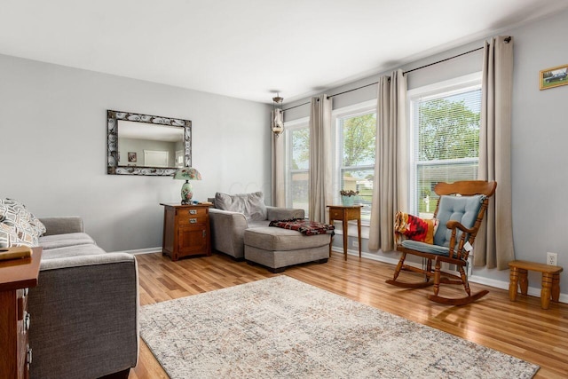 living area featuring baseboards and light wood finished floors