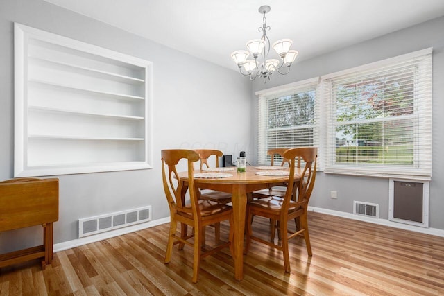 dining room with baseboards, a notable chandelier, visible vents, and wood finished floors
