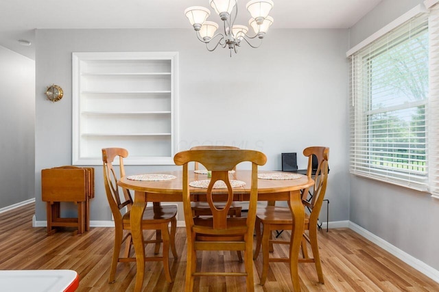 dining space with baseboards, wood finished floors, and a chandelier