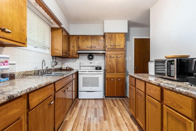 kitchen featuring electric range, brown cabinets, a sink, stainless steel microwave, and light wood-style floors