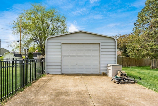detached garage featuring concrete driveway and fence