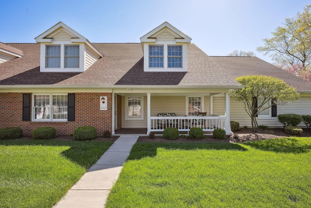 view of front facade featuring roof with shingles, covered porch, and a front lawn