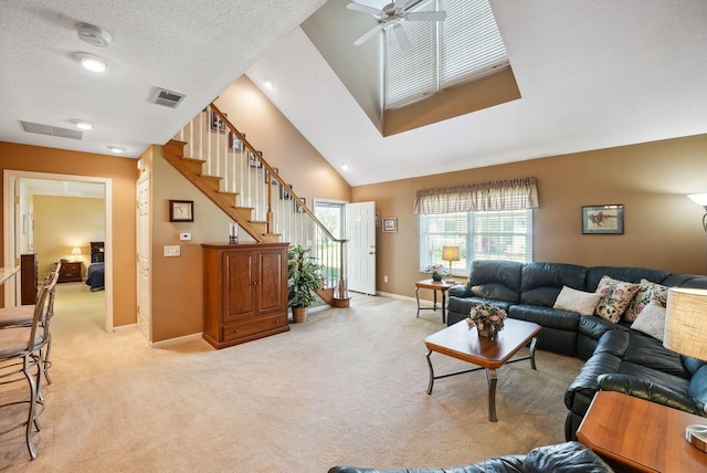 living room featuring ceiling fan, visible vents, light carpet, and stairway