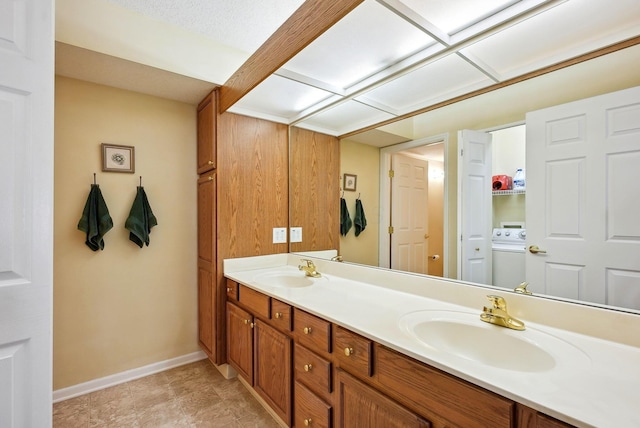 full bathroom featuring double vanity, baseboards, washer / dryer, and a sink