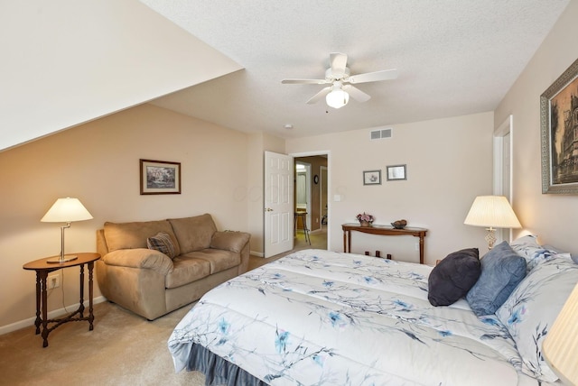 bedroom featuring visible vents, light carpet, baseboards, ceiling fan, and a textured ceiling