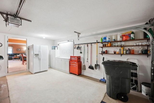garage with baseboards and white refrigerator with ice dispenser