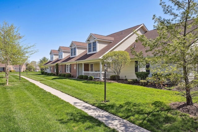 view of front of house with covered porch, a shingled roof, and a front lawn