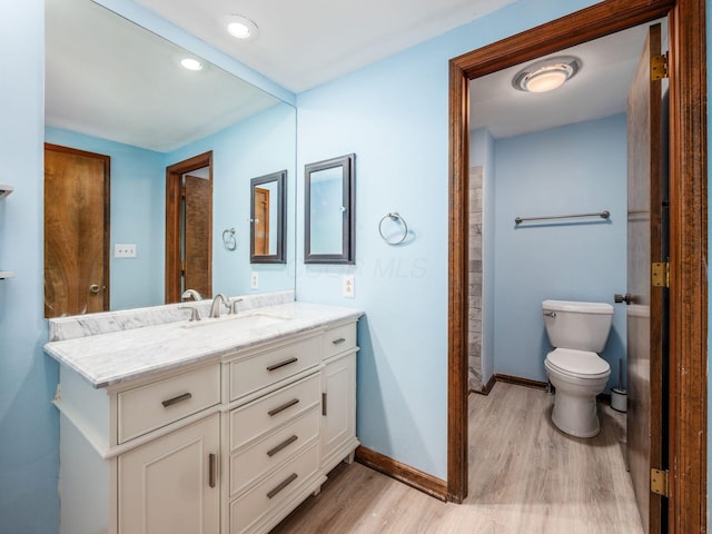 bathroom with wood finished floors, baseboards, vanity, toilet, and recessed lighting