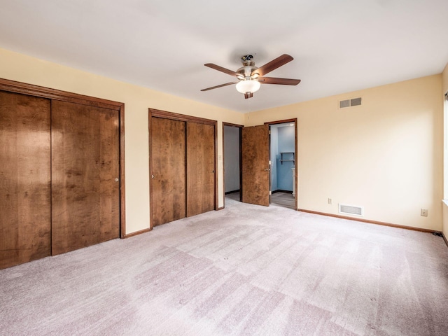 unfurnished bedroom with two closets, carpet flooring, and visible vents