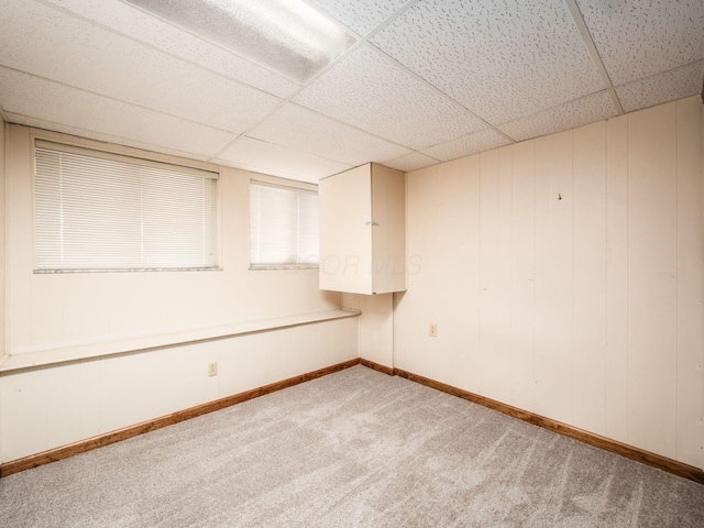 carpeted spare room with baseboards and a drop ceiling