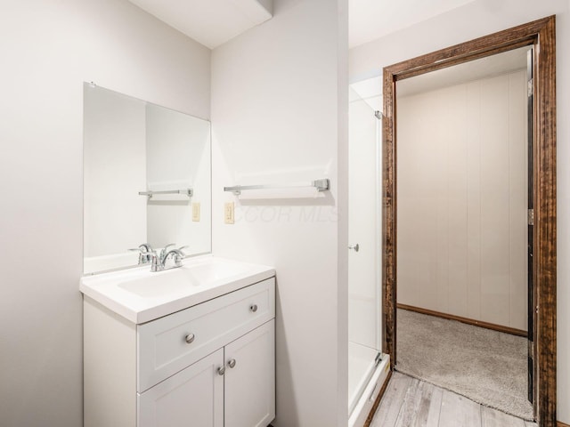 full bathroom with vanity, a stall shower, and wood finished floors
