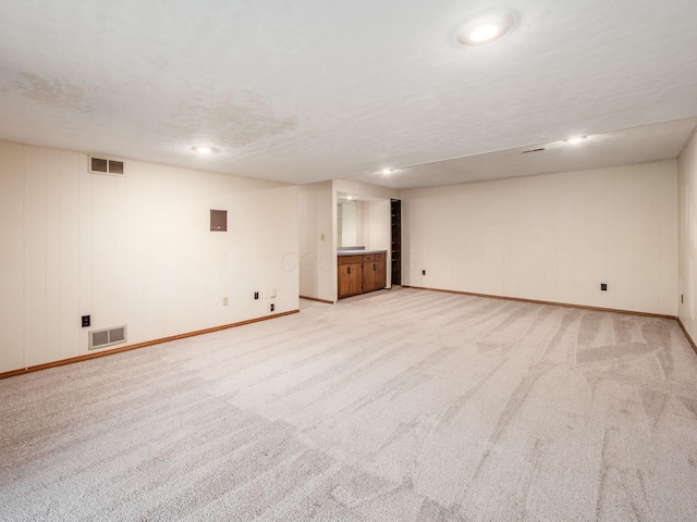 finished below grade area featuring light colored carpet, baseboards, and visible vents