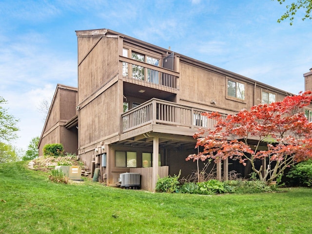 rear view of house with a lawn, central AC unit, a wooden deck, and a balcony