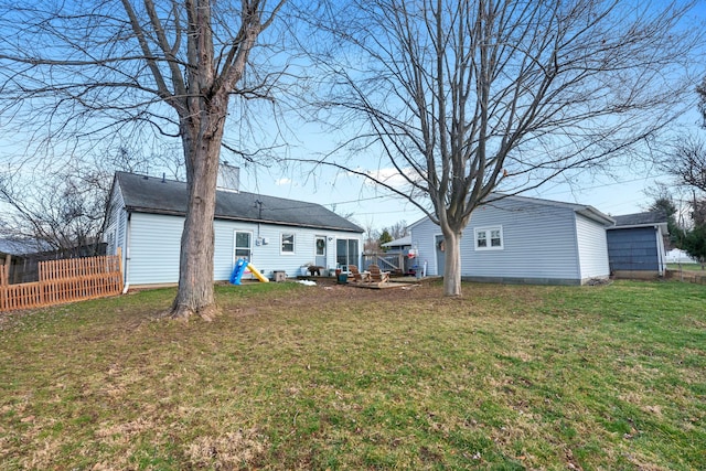 rear view of property featuring a lawn and fence