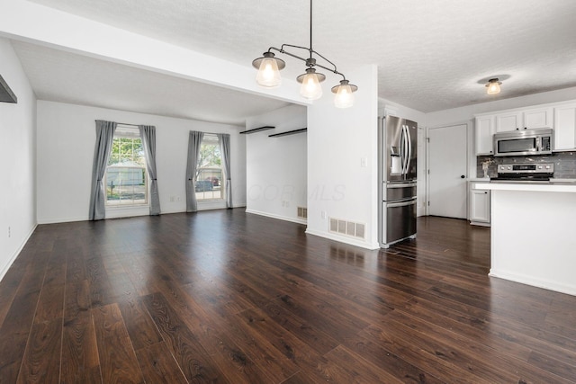 unfurnished living room featuring dark wood-style flooring, a textured ceiling, and visible vents