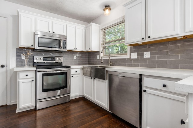 kitchen with a sink, dark wood finished floors, appliances with stainless steel finishes, and white cabinetry