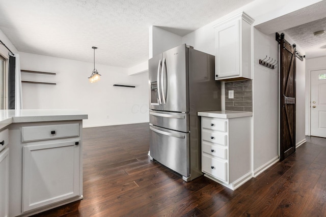 kitchen with stainless steel fridge, a barn door, light countertops, a textured ceiling, and dark wood finished floors