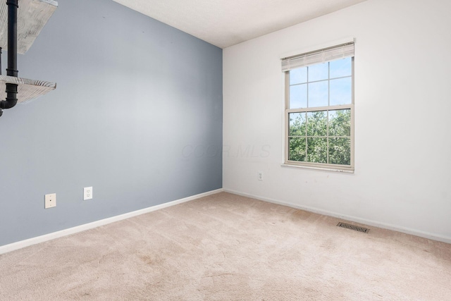 carpeted empty room with visible vents, a wood stove, and baseboards