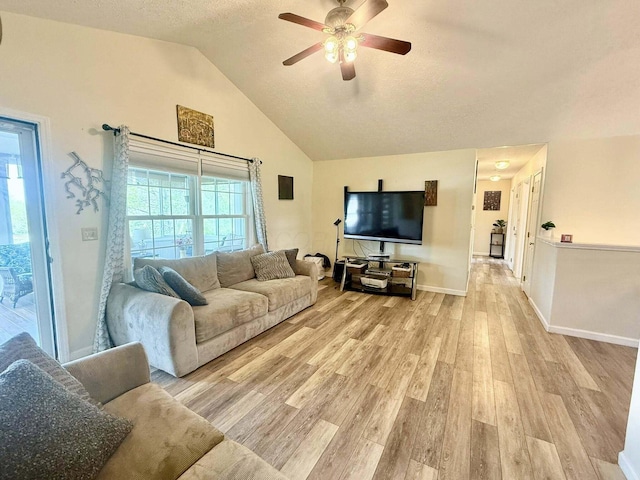 living area with lofted ceiling, baseboards, a textured ceiling, a ceiling fan, and light wood finished floors