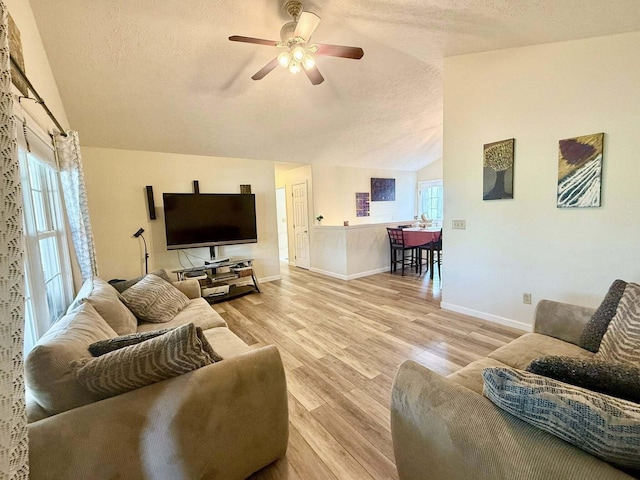 living area with a textured ceiling, vaulted ceiling, and a healthy amount of sunlight