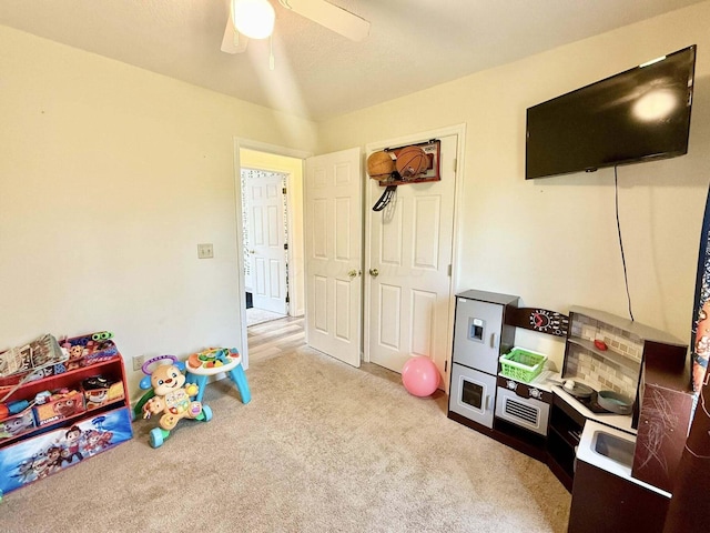 recreation room with light colored carpet and a ceiling fan