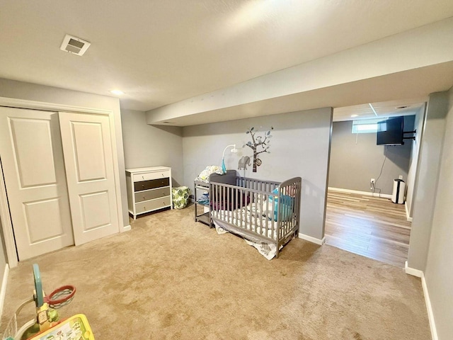 bedroom with visible vents, a nursery area, baseboards, a closet, and carpet