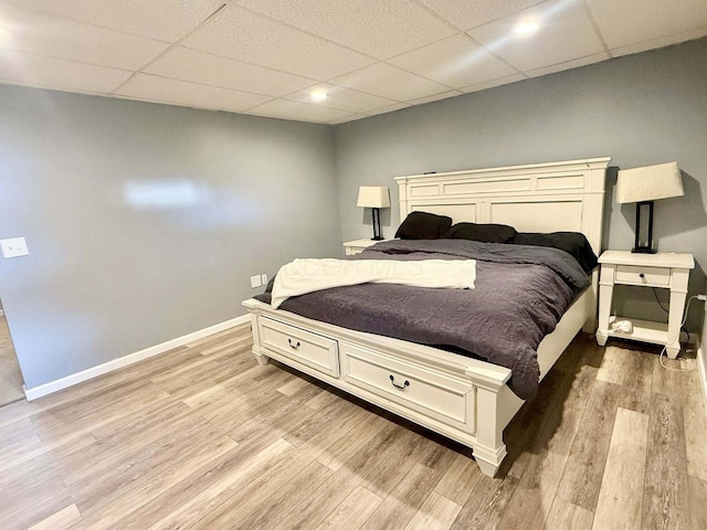 bedroom featuring light wood-type flooring, recessed lighting, baseboards, and a paneled ceiling
