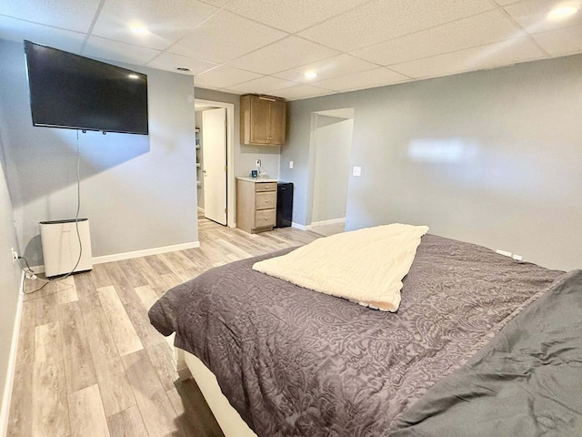 bedroom featuring baseboards, recessed lighting, light wood finished floors, and a paneled ceiling