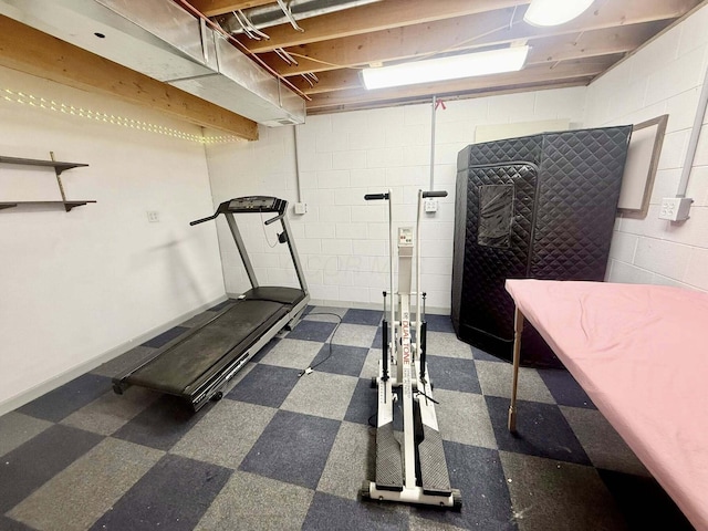 exercise area featuring concrete block wall and tile patterned floors