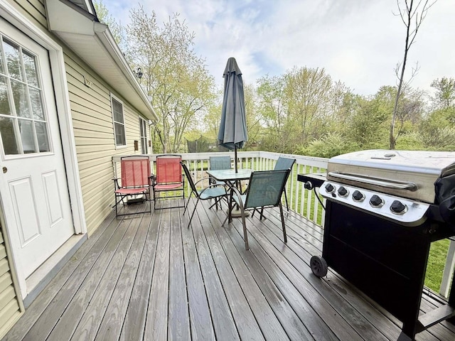 wooden deck with outdoor dining area and a grill