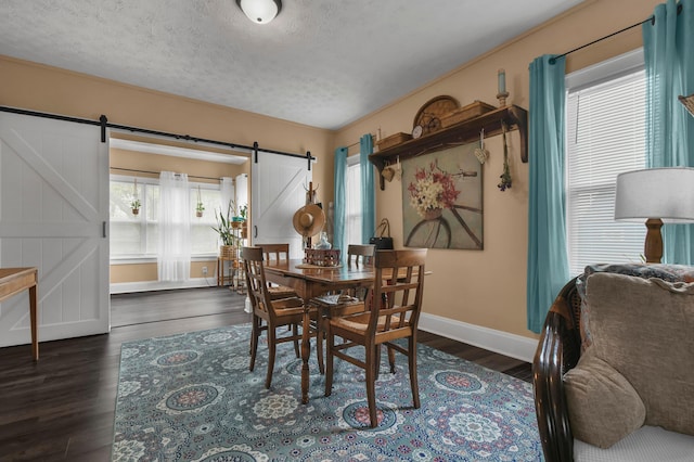 dining space featuring baseboards, a barn door, a wealth of natural light, and wood finished floors