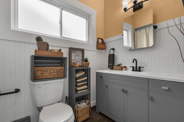 bathroom featuring wainscoting, vanity, toilet, wood finished floors, and a baseboard radiator