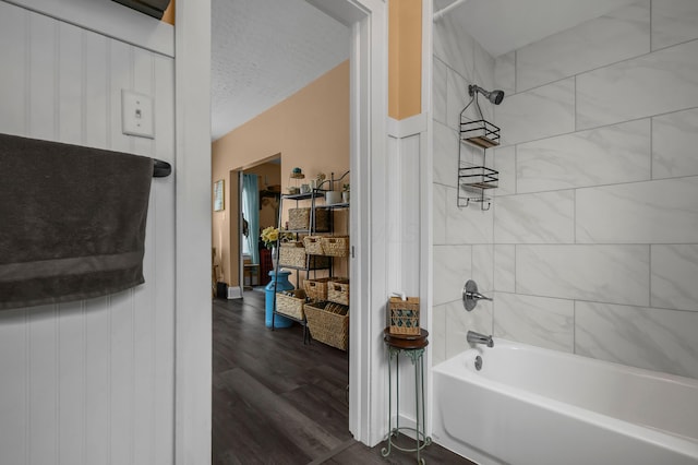 full bath featuring a textured ceiling, washtub / shower combination, and wood finished floors