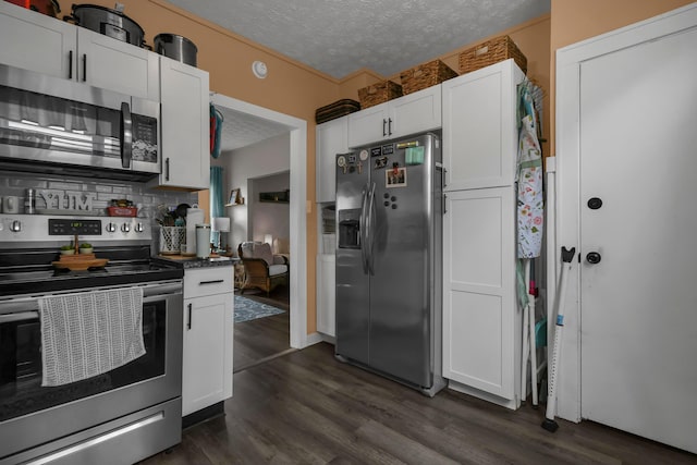 kitchen featuring dark countertops, appliances with stainless steel finishes, a textured ceiling, white cabinetry, and dark wood-type flooring
