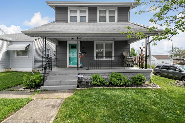 view of front facade featuring a porch, roof with shingles, and a front yard