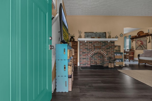 interior space with a textured ceiling, a brick fireplace, and wood finished floors